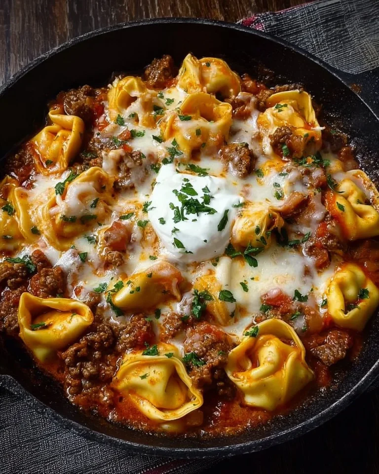 Cheesy beef enchilada tortellini served in a bowl topped with herbs and cheese