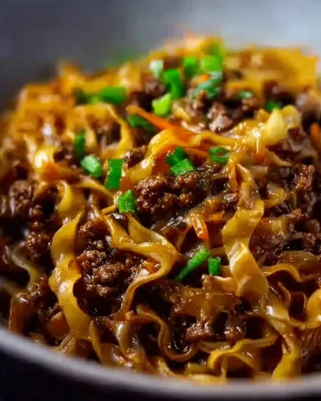 Plate of Mongolian Ground Beef Noodles topped with green onions and sesame seeds.