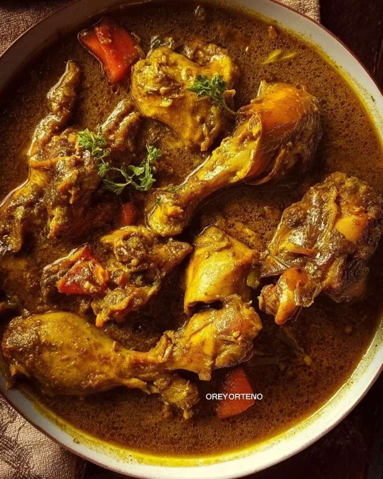 Bowl of authentic Jamaican Curry Chicken garnished with fresh herbs