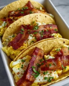 Plate of baked breakfast tacos filled with eggs, cheese, and toppings.