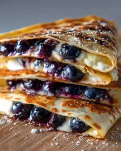 Delicious blueberry breakfast quesadilla served on a plate with fresh blueberries.