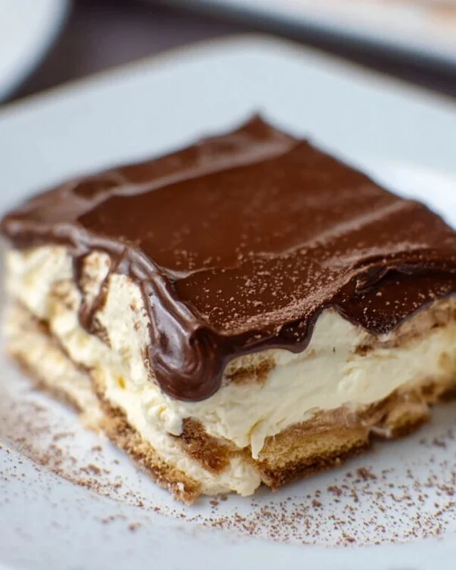 No-bake chocolate eclair cake topped with chocolate glaze and whipped cream
