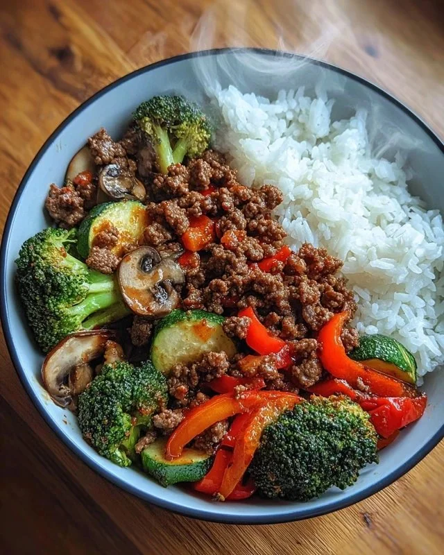 Spicy beef stir-fry bowl with garlic vegetables and rice.