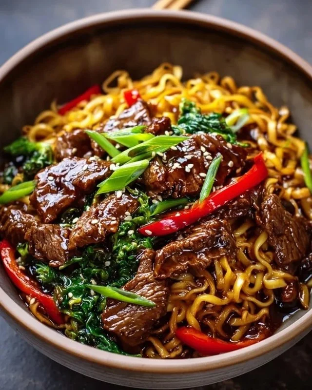 Delicious sticky beef noodles served in a bowl with fresh herbs and vegetables.