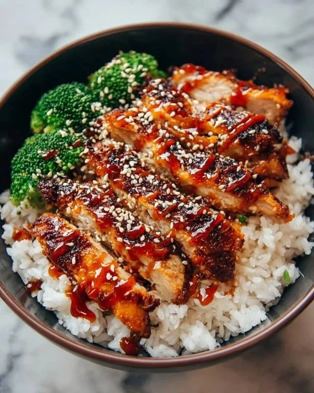 Delicious sticky chicken rice bowls topped with fresh herbs and vegetables.