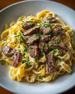 Creamy steak pasta with garlic sauce garnished with herbs