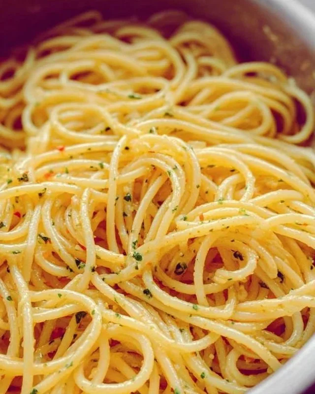 A plate of spaghetti with garlic and oil garnished with parsley.