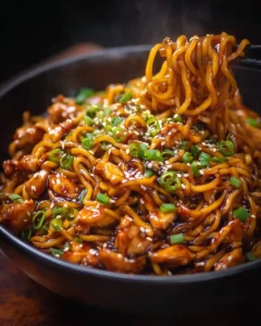 Sticky garlic chicken noodles garnished with fresh herbs