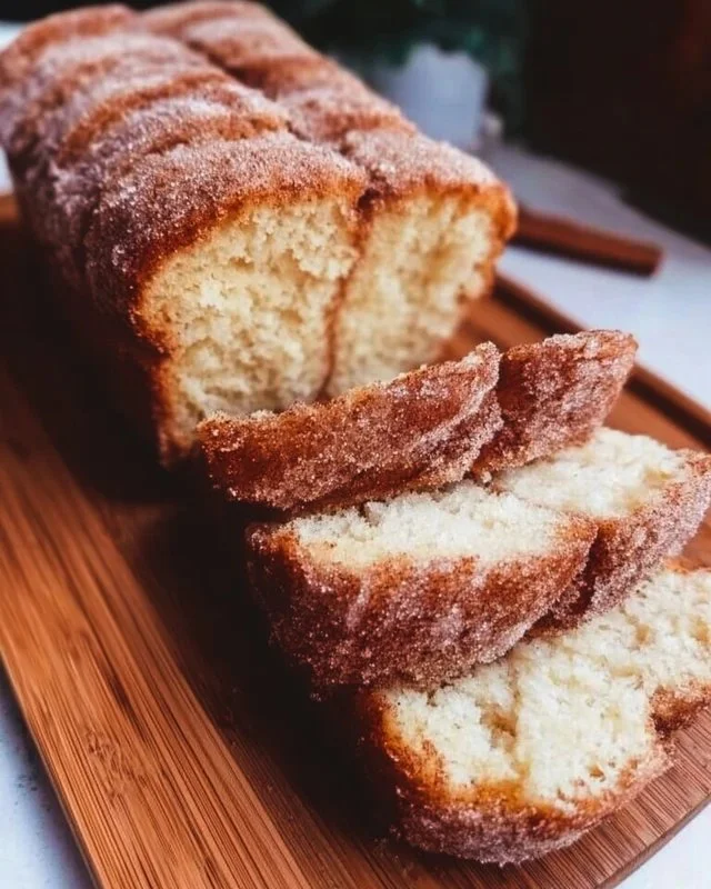 A loaf of cinnamon sugar donut bread garnished with cinnamon and sugar sprinkles.