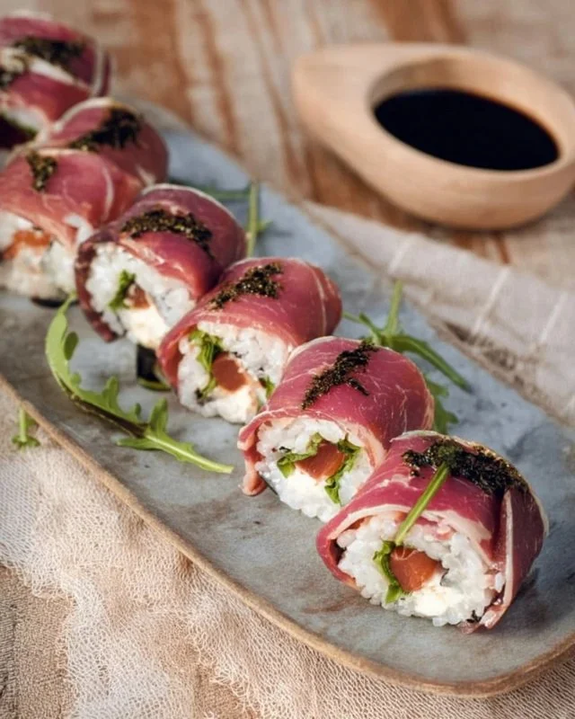 Italian charcuterie sushi rolls with cured meats, cheese, and fresh vegetables.