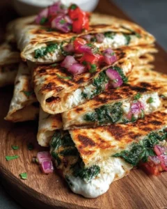 Mediterranean quesadillas with spinach, feta, mozzarella, and red onion on a plate.