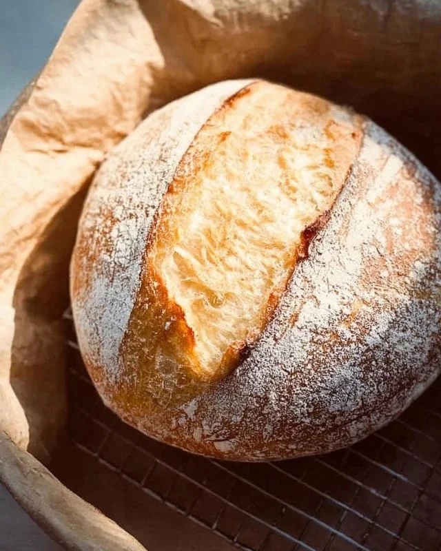 A beautifully baked no-fail sourdough bread loaf on a wooden cutting board.