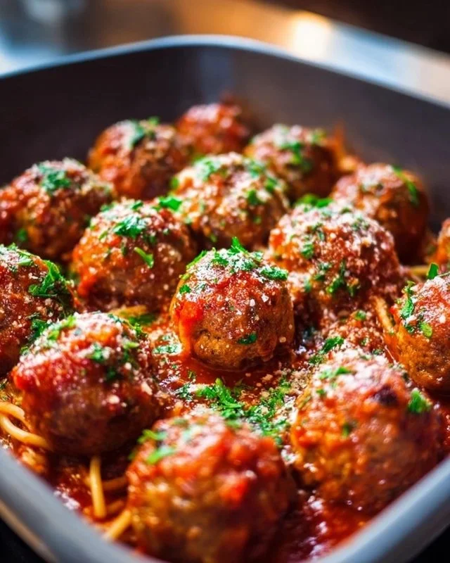 Delicious oven-baked Italian meatballs on a plate garnished with herbs.