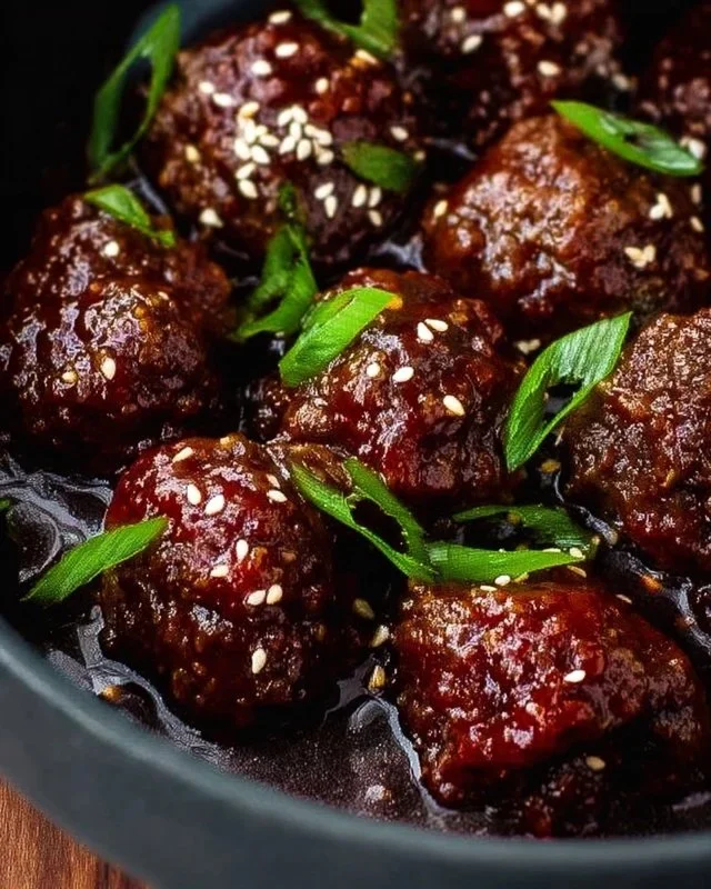 Sticky Mongolian beef meatballs served in a bowl with sauce and garnish.