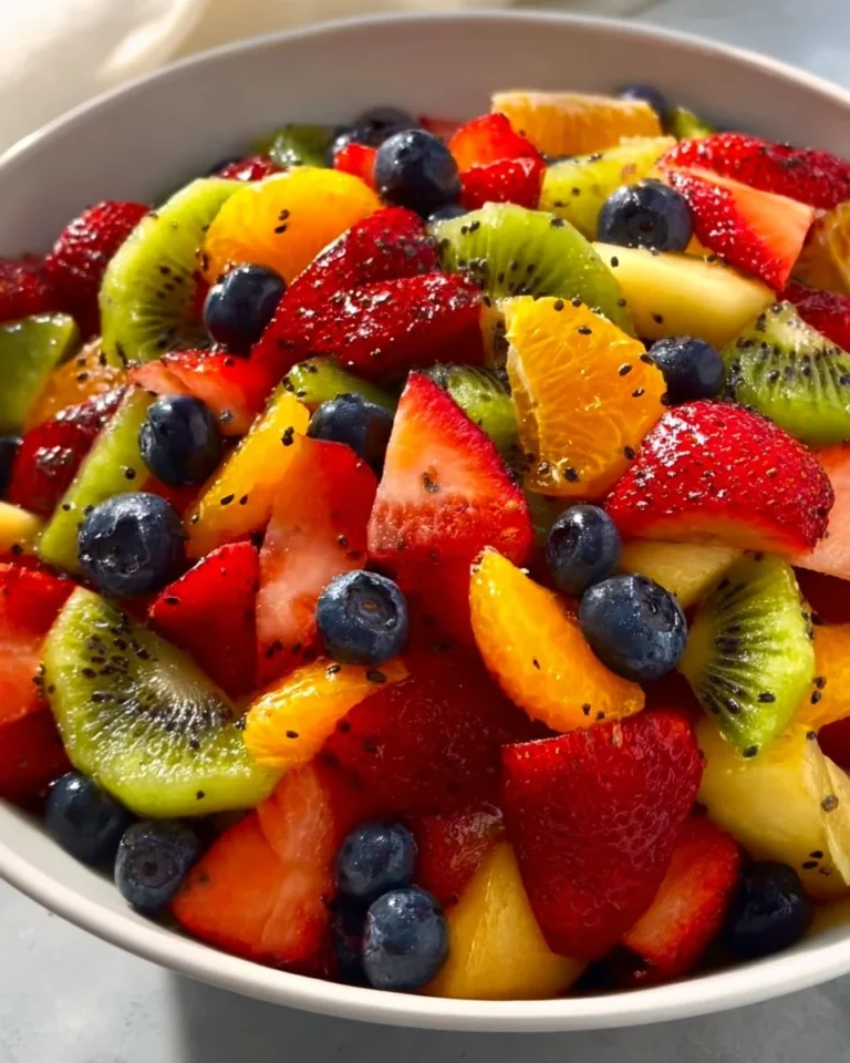 Fresh fruit salad topped with honey lime poppy seed dressing in a bowl.