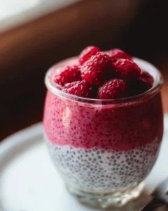 Bowl of Raspberry Chia Pudding topped with fresh raspberries and maple syrup
